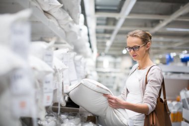 Modern ev mobilyası deposunda yatağı için doğru yastık seçme güzel genç bayan (Renk tonlu görüntü; sığ Dof)