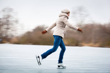 açık havada bir gölet üzerinde soğuk bir kış gününde genç kadın buz