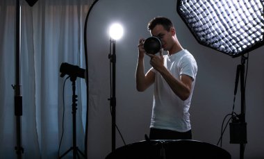 Fotoğraf çekmek genç pro fotoğrafçı ile dijital fotoğraf makinesi - Dslr ve onun iyi donanımlı Studio büyük bir telefoto lens (Renk tonlu görüntü; sığ Dof)