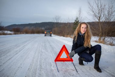 Bir uyarı üçgen yukarı ayarlama ve arabasını ortasında hiçbir yerde bir dondurucu kış gününde bozuldu sonra yardım için arıyor genç kadın