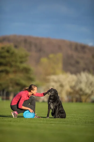 年轻女子带着她的黑狗在户外玩耍 在公园里玩飞盘 浅薄的 Dof 锐利的焦点 — 图库照片