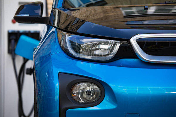 Электропитание для зарядки электромобилей. Электростанция зарядки автомобилей. Крупный план электропитания, подключенного к заряжаемому электромобилю.