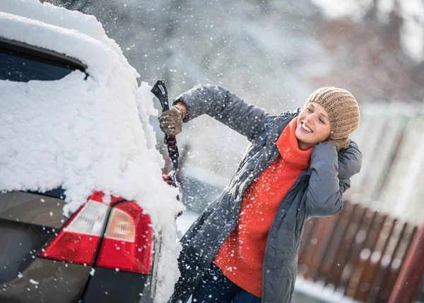 漂亮的年轻女子在暴风雪之后从雪中打扫卫生着自己的车 色彩柔和的图像 — 图库照片