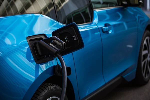 Elektrikli araba şarjı için güç kaynağı. Elektrikli araba şarj istasyonu. Şarj edilen bir elektrikli arabaya takılan güç kaynağını kapatın..