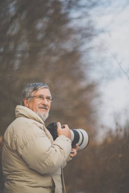Son sınıf öğrencisi zamanını en sevdiği hobisine harcıyor: Fotoğrafçılık - dijital kamerası / DSLR ve büyük bir telefoto lensi ile dışarıda fotoğraf çekiyor.