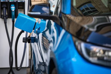 Elektrikli araba şarjı için güç kaynağı. Elektrikli araba şarj istasyonu. Şarj edilen bir elektrikli arabaya takılan güç kaynağını kapatın..