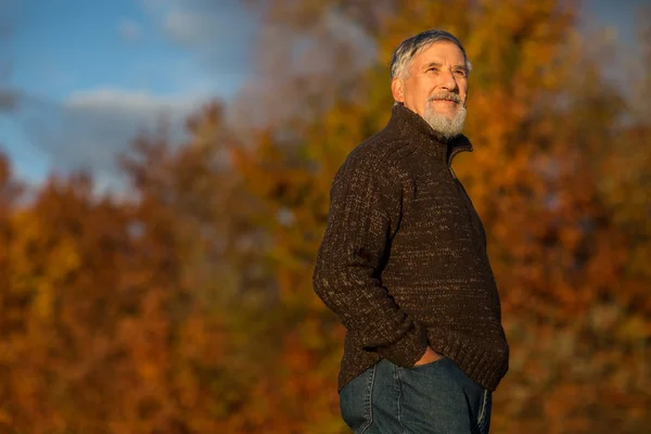 Porträtt av en äldre man utomhus, promenader i en park — Stockfoto