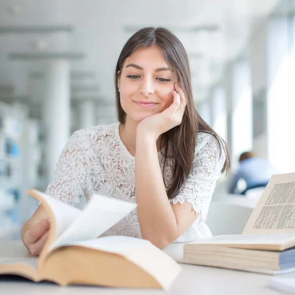 Hübsche, junge Studentin auf der Suche nach einem Buch in der Bibliothek, — Stockfoto