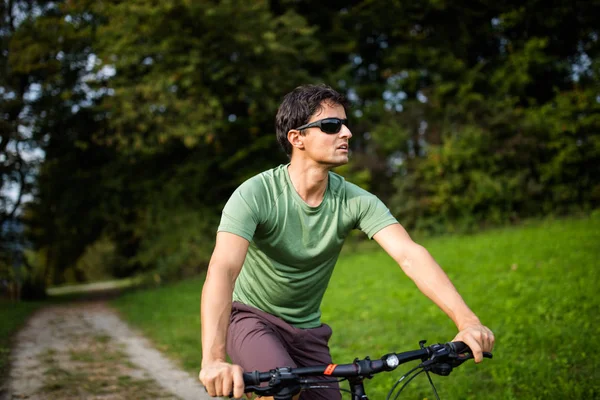 Młody człowiek jazda jego rower górski na zewnątrz na drodze leśnej — Zdjęcie stockowe