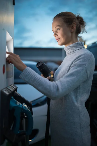 Νεαρή γυναίκα φόρτισης ένα ηλεκτρικό όχημα. Έννοια κοινής χρήσης αυτοκινήτων. — Φωτογραφία Αρχείου