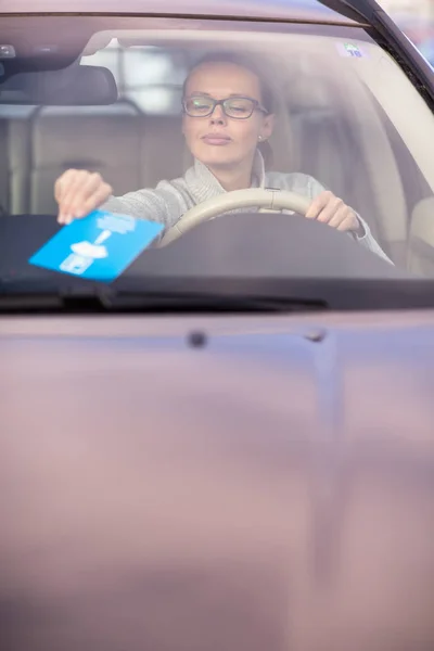 Pretty, ung kvinna att sätta den nödvändiga parkerings klockan bakom vindrutan — Stockfoto