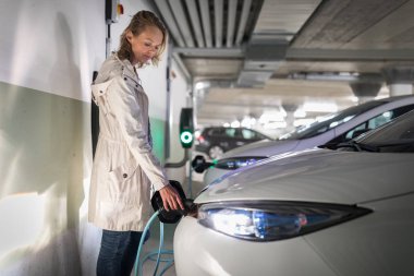 Genç kadın bir yeraltı garajı bir elektrikli araç şarj