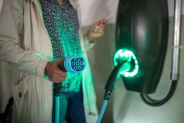 Genç kadın bir yeraltı garajı bir elektrikli araç şarj