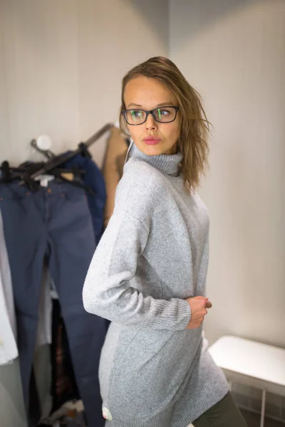 Junge Frau kauft in einem Modegeschäft ein und probiert ein paar Klamotten an — Stockfoto