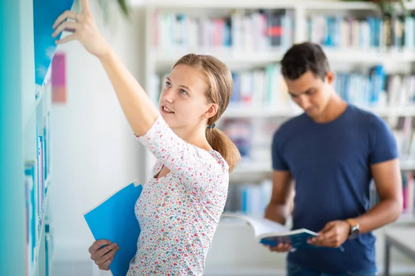 Leuke vrouwelijke universiteit / middelbare school student met boeken in de bibliotheek — Stockfoto