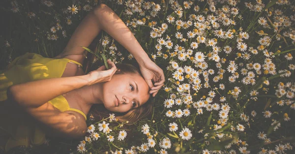 Porträt einer jungen Frau, die inmitten von Blumen liegt — Stockfoto