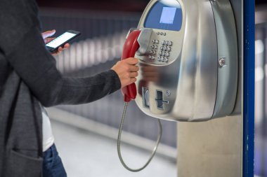 Havaalanında ankesörlü telefon kullanan genç bir kadın.