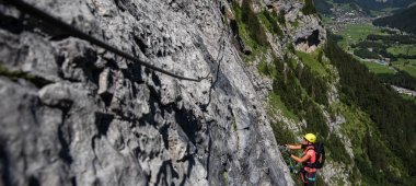 Güzel, kadın dağcı bir via ferrata bir kaya tırmanışı -