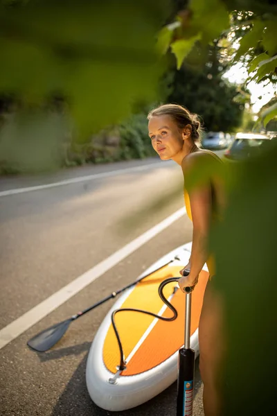 Hübsche, junge Frau paddelt an Bord — Stockfoto