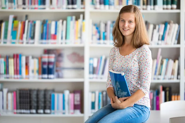 Bonito estudante universitário / colegial feminino com livros na biblioteca — Fotografia de Stock