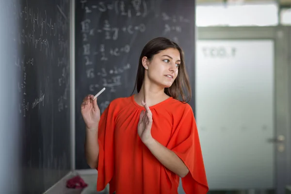 Guapa, joven estudiante universitaria escribiendo en la pizarra — Foto de Stock