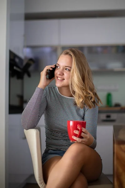 Adolescente appelant sur son téléphone portable tout en ayant une tasse de thé — Photo