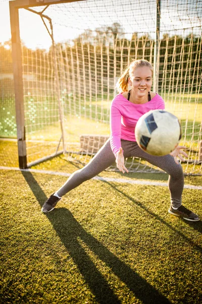 Tiener vrouwelijke keeper vangt een schot tijdens een voetbalspel — Stockfoto