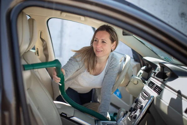 Mujer bonita y de mediana edad que limpia al vacío el interior de un coche —  Fotos de Stock