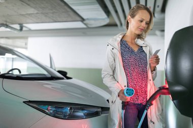 Genç kadın bir yeraltı garajı bir elektrikli araç şarj