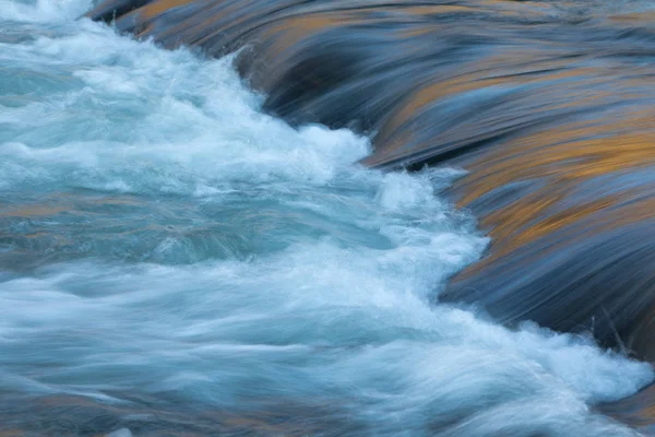 Flusswasser fließt mit Licht, das seine Oberfläche reflektiert — Stockfoto