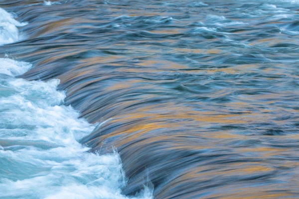 Flusswasser fließt mit Licht, das seine Oberfläche reflektiert — Stockfoto