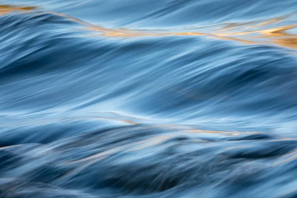 Flusswasser fließt mit Licht, das seine Oberfläche reflektiert — Stockfoto