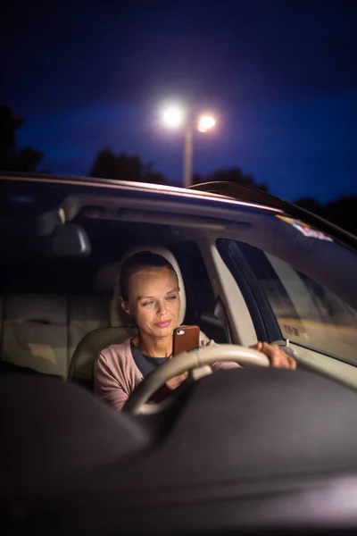 Молодая женщина-водитель играет со своим телефоном — стоковое фото