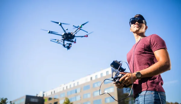 Knappe jonge man vliegen een drone buitenshuis — Stockfoto