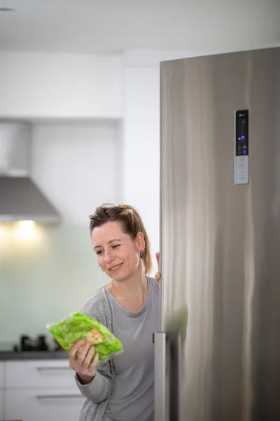 Pretty, young woman taking groceries out of the fridge — Stock Photo, Image