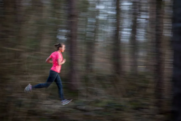 Ung kvinna kör utomhus i en skog, går fort — Stockfoto