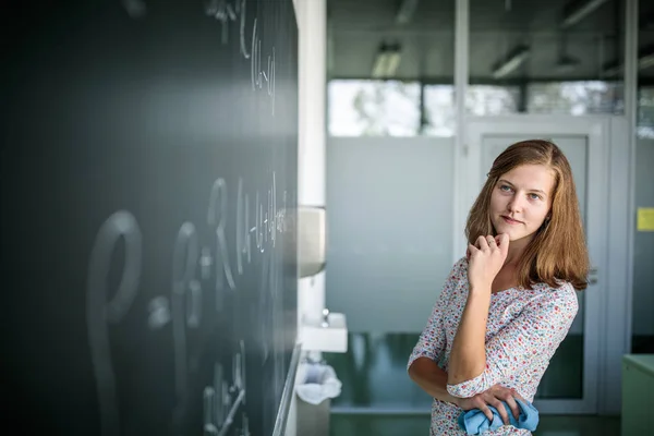 Όμορφη, νεαρή μαθήτρια μπροστά από έναν μαυροπίνακα. — Φωτογραφία Αρχείου