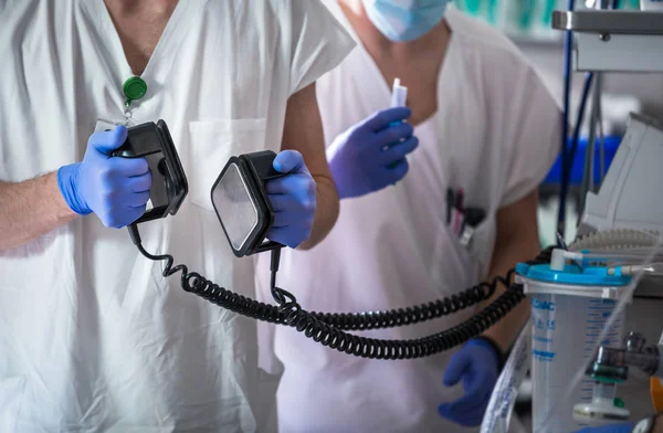 Doctor holding defibrillator electrods, performing defibrillatio — Stock Photo, Image