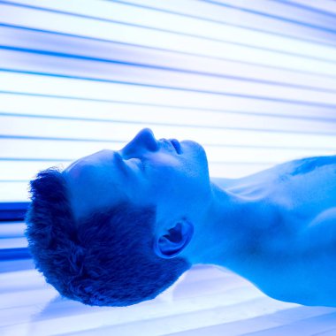 Yakışıklı delikanlı bir bronzlaşma oturum sırasında rahatlatıcı