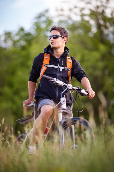 Handsome young man biking in the countryside