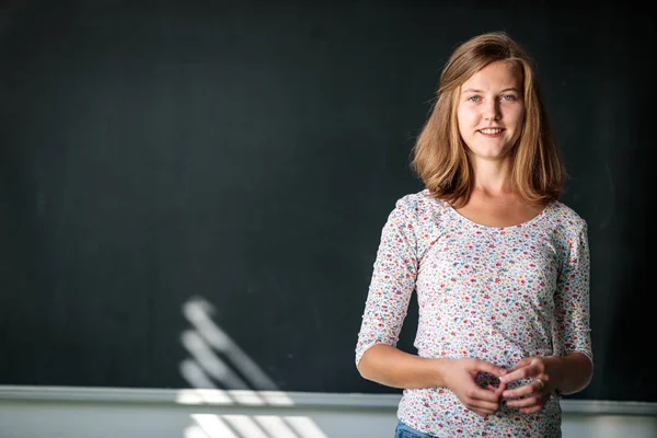 Mooie, jonge vrouwelijke student/jonge theekopjes voor een Blackboard — Stockfoto