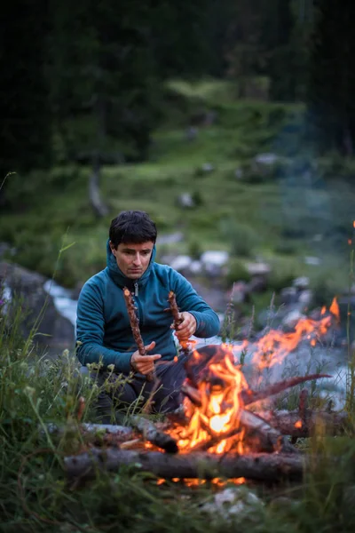 屋外でキャンプをしながら火を作る若者 — ストック写真