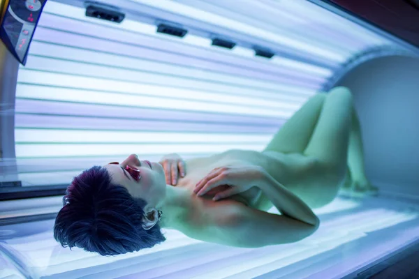 Ładna, młoda kobieta opalona skórą w nowoczesnym solarium — Zdjęcie stockowe