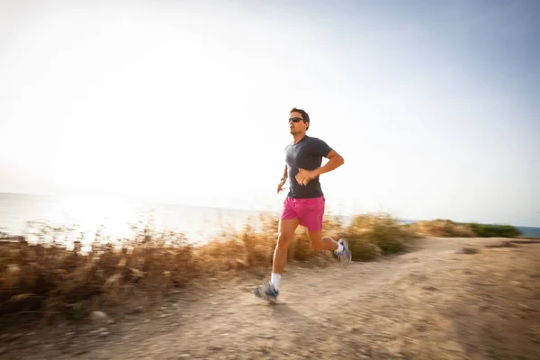 Caucásico joven corriendo en un camino de costa — Foto de Stock