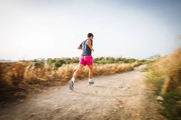 Caucasian young man running on a seacost path — Stock Photo, Image