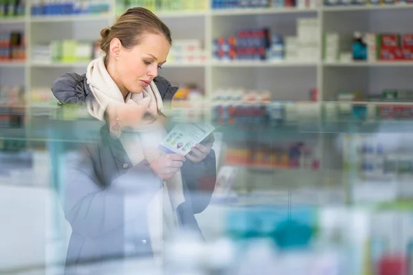 Mujer joven que busca las píldoras adecuadas en una farmacia moderna — Foto de Stock