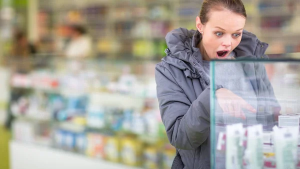 Mujer joven que busca las píldoras adecuadas en una farmacia moderna — Foto de Stock