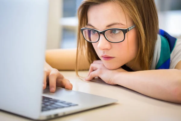 Vacker, kvinnlig collegestudent i ett bibliotek, letar du efter en bok — Stockfoto