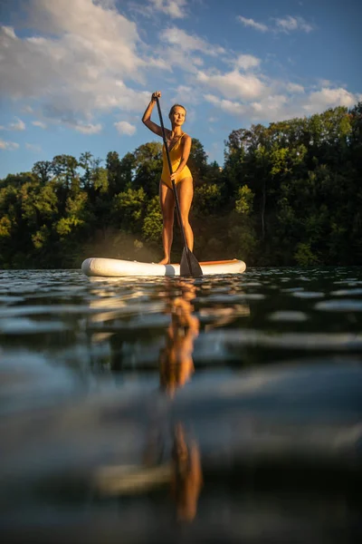 Bella, giovane donna pagaia imbarco su un bel lago — Foto Stock