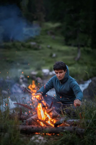 Giovane che fa fuoco mentre si accampa all'aperto — Foto Stock